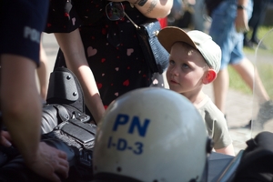 dziecko stoi przy stole na stanowisku policji, na stole leżą części umundurowania i wyposażenia