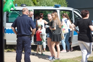 radiowóz policji typu bus, przed nim stoi młodzież i policjant