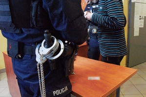 policjant w pomieszczeniu dla osób zatrzymanych wraz zatrzymanym mężczyzną