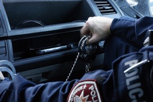 zdjęcie przedstawia: umundurowany policjant trzymający kajdanki w ręce