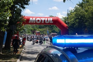 zdjęcie przedstawia: zbliżenie na policyjny sygnał niebieski błyskowy a w tle kolumna motocykli