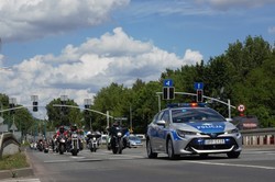 zdjęcie przedstawia: policyjny radiowóz oraz kolumna przejeżdżających motocykli