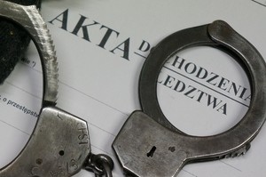 zdjęcie przedstawia kajdanki leżące na aktach