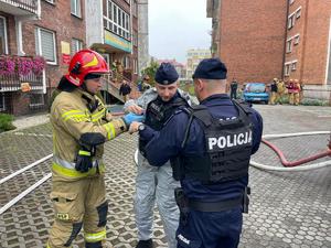 zdjęcie przedstawia policjantów z czego jeden ubiera skafander