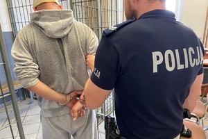 zdjęcie przedstawia: policjanta trzymającego mężczyznę z założonymi kajdankami