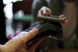 grafika przedstawia zbliżenie telefonu do terminala płatniczego