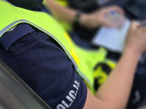zdjęcie przedstawia policjanta piszącego w notatniku