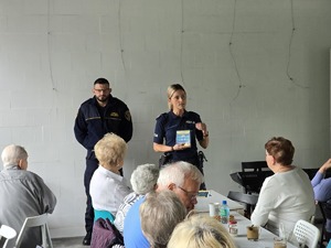 zdjęcie przedstawia policjantkę rozmawiającą z mieszkańcami