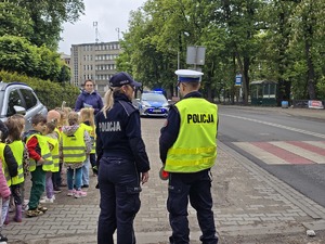 zdjęcie przedstawia policjantów z dziećmi ubranymi w kamizelki odblaskowe podczas akcji profilaktycznej