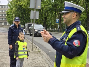 zdjęcie przedstawia policjanta tłumaczącego dzieciom