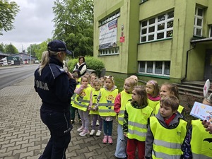 zdjęcie przedstawia policjantów z dziećmi ubranymi w kamizelki odblaskowe podczas akcji profilaktycznej