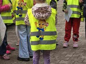 zdjęcie przedstawia dzieci ubrane w kamizelki odblaskowe podczas akcji profilaktycznej
