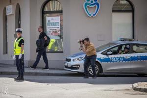 zdjęcie przedstawia policjantkę zabezpieczającą skrzyżowanie, radiowóz i mężczyznę robiącego zdjęcia