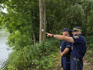 zdjęcie przedstawia policjanta i strażnika miejskiego nad stawem