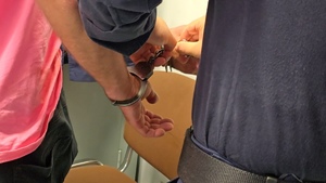 zdjęcie przedstawia policjanta rozpinającego kajdanki