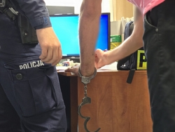 zdjęcie przedstawia policjanta i zatrzymanego mężczyznę który podpisuje dokumenty