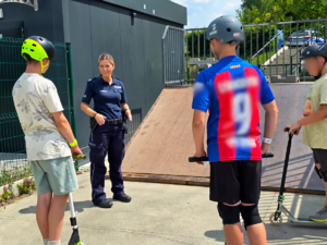 zdjęcie przedstawia policjantkę i chłopaków na skateparku