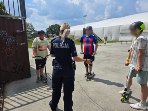 zdjęcie przedstawia policjantkę i chłopaków na skateparku