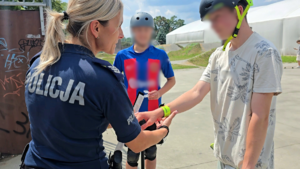 zdjęcie przedstawia policjantkę i chłopaków na skateparku