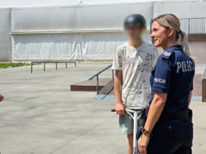 zdjęcie przedstawia policjantkę i chłopaków na skateparku
