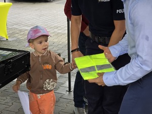 zdjęcie przedstawia policjantkę i dziecko któremu wręczane są nagrody