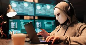 zdjęcie przedstawia mężczyznę w masce przed komputerem