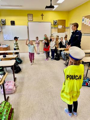 zdjęcie przedstawia: policjanta rozmawiającego z dziećmi w szkole