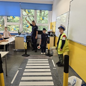 zdjęcie przedstawia: policjantkę i uczniów przebranych za policjantów