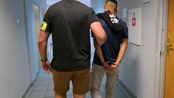 zdjęcie przedstawia nieumundurowanego policjanta trzymającego mężczyznę z założonymi kajdankami