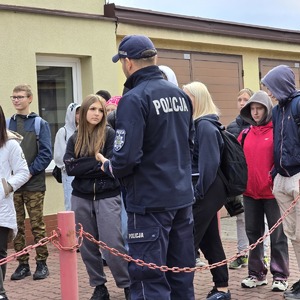 zdjęcie przedstawia grupę uczniów i policjanta na terenie szkoły policji w katowicach
