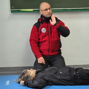 zdjęcie przedstawia policjanta prowadzącego szkolenie z pierwszej pomocy