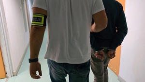 zdjęcie przedstawia jak nieumundurowany policjant trzyma zatrzymanego mężczyznę