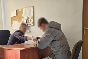 zdjęcie przedstawia nieumundurowanego policjanta stawiającego zarzuty mężczyźnie