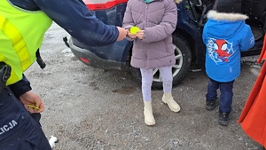 zdjęcie przedstawia policjanta rozdającego odblaski