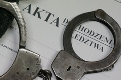 zdjęcie przedstawia akta dochodzeniowe i kajdanki