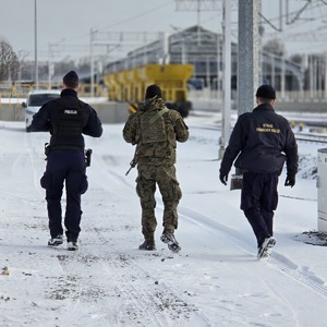 zdjęcie przedstawia policjanta, żołnierza i funkcjonariusza straży ochrony kolei podczas patrolu na torowisku