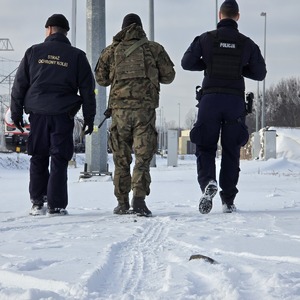 zdjęcie przedstawia policjanta, żołnierza i funkcjonariusza straży ochrony kolei podczas patrolu na torowisku