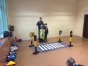 zdjęcie przedstawia policjanta rozmawiającego z dziećmi w szkole