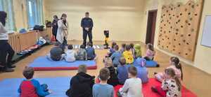 zdjęcie przedstawia policjanta rozmawiającego z dziećmi w szkole