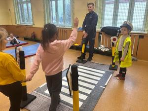 zdjęcie przedstawia policjanta rozmawiającego z dziećmi w szkole