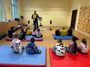 zdjęcie przedstawia policjanta rozmawiającego z dziećmi w szkole