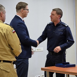 zdjęcie przedstawia prezydenta i strażaka żegnających naczelnika