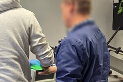 zdjęcie przedstawia mężczyznę któremu policjant pobiera odciski palców