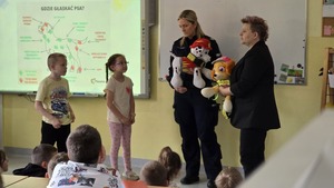 zdjęcie przedstawia policjantkę i pracownika socjalnego rozmawiającego z uczniami
