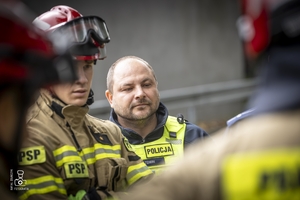 zdjęcie przedstawia policjantów i strażaków omawiających ćwiczenie
