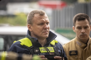 zdjęcie przedstawia policjantów i strażaków stojących przy wraku samochodu i omawiających ćwiczenie