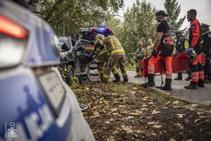 zdjęcie przedstawia wrak samochodu i strażaków rozcinających drzwi