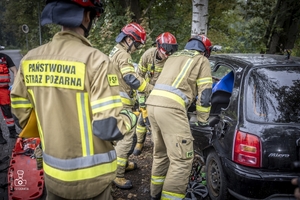 zdjęcie przedstawia wrak samochodu i strażaków rozcinających drzwi
