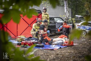zdjęcie przedstawia poszkodowanego, strażaków i medyków udzielających mu pomocy