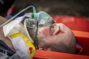 zdjęcie przedstawia poszkodowanego na desce ortopedycznej z maską z tlenem